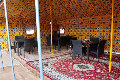 BadīyahRashid Desert Private Camp的帐篷内的用餐室配有桌椅