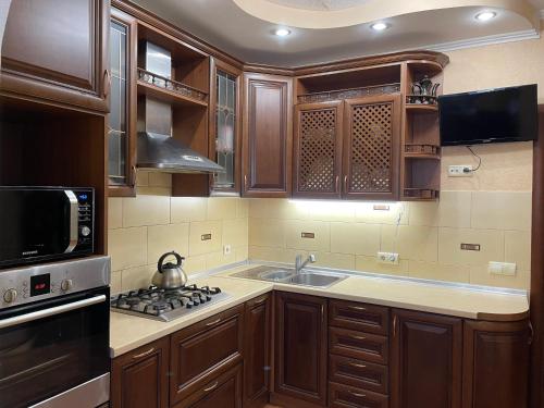 鲍里斯皮尔Boryspil Airport Luxury apartment的厨房配有木制橱柜、水槽和炉灶。