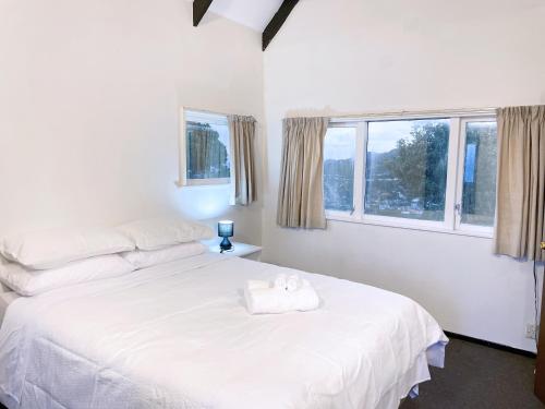 惠灵顿NO PARTY ALLOWED,Sea view 5 bedroom house的卧室配有白色的床和2扇窗户。