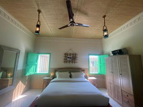 Al ḨamrānīyahAl Bait resort with private swimming pools -HRS stables的一间卧室配有一张带绿色百叶窗和天花板的床