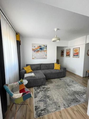 雅西Cozy Apartment - near Airport and Palas Mall的客厅配有灰色的沙发和黄色的枕头。