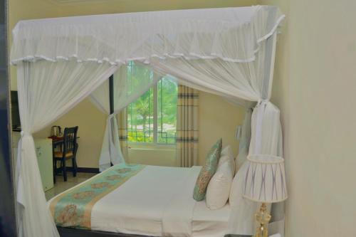 桑给巴尔Royal Cliff Zanzibar的一间卧室配有一张天蓬床和窗户