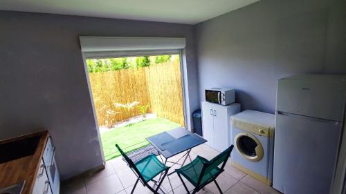 MontjolyStudio confort avec jardinet的厨房配有桌椅和洗衣机。