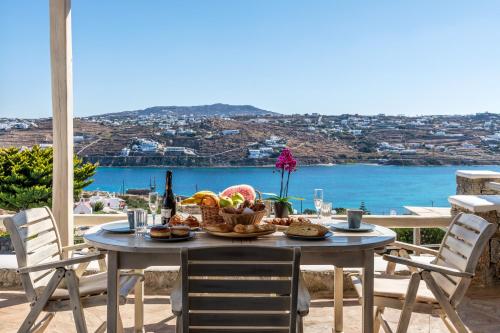米克诺斯城Yalos Mykonos Ornos Pouli private apartments w shared swimming pool的一张带食物的桌子,享有海景