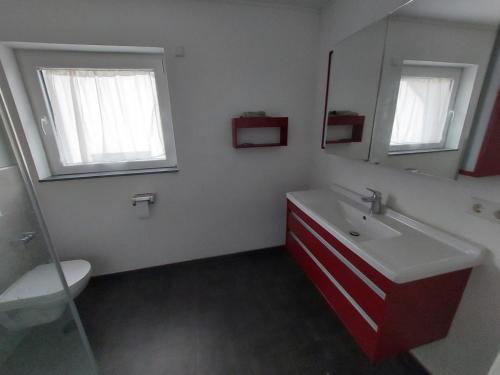 VichtenComfortable room with double bed的浴室设有红色和白色的盥洗盆和镜子