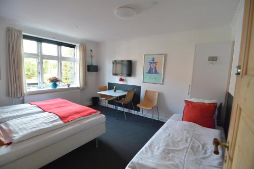 欧登塞Billesgade Rooms的一间卧室设有两张床、一张桌子和一个窗口