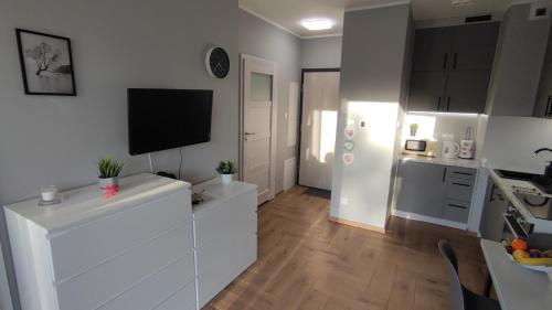 比得哥什Apartament Orla 47F Perłowa Dolina的一间厨房,配有白色橱柜和墙上的电视