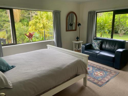 芒奥努伊Harbour View Retreat Mangonui的一间卧室配有一张床、一张沙发和窗户。