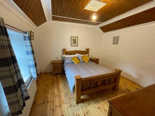 多尼戈尔John the mills cottage spaHot tub private beach的一间卧室配有一张带黄色枕头的床。