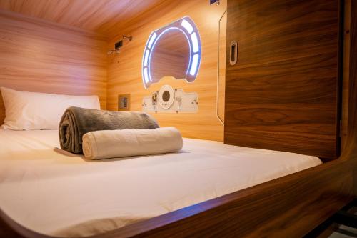 哥打京那巴鲁Jpod Capsule Hotel的一个小房间的一个床位,设有窗户