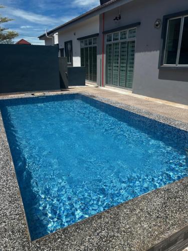 Kampong HilirVilla Pool Kepala Batas的房子前面的蓝色游泳池