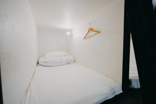 东京unito light SHIMBASHI的白色的房间,设有一张床和墙上的衣架