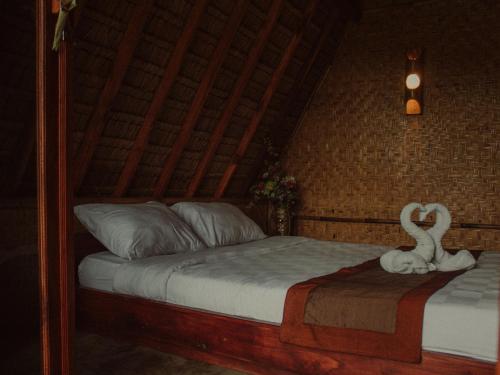 姆杜克Da'kayu Glamping的一间卧室配有一张床铺,上面有天鹅雕像
