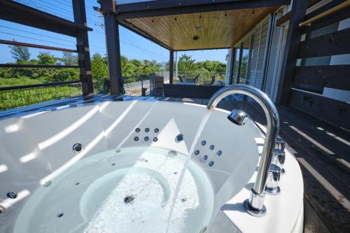 宜野座Beach Side Secret -SEVEN Hotels and Resorts-的房屋甲板上的按摩浴缸