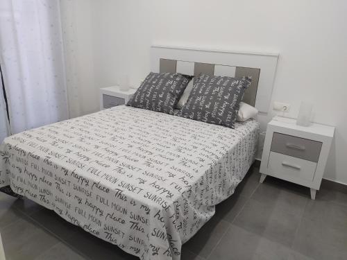 帕洛斯德拉夫龙特拉Excelente piso con aparcamiento privado的一间卧室配有带2个床头柜和2个枕头的床