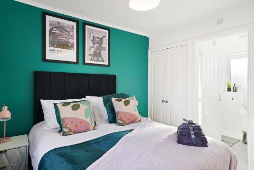 伍尔弗汉普顿Ideal 3 bed House in Wolverhampton - Parking的一间卧室设有绿色的墙壁和一张带枕头的床