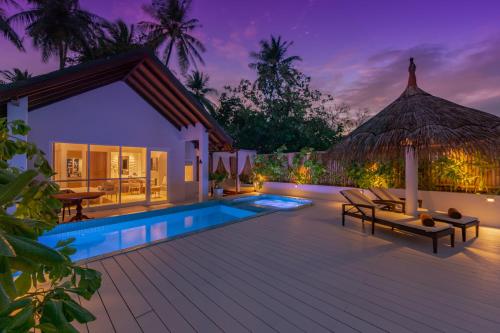 北马累环礁Malahini Kuda Bandos Resort的夜间带游泳池的别墅