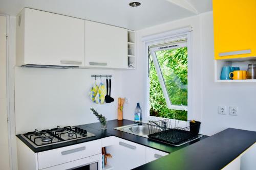 马佐Casitas Mobil Home的厨房配有白色橱柜和黑色台面