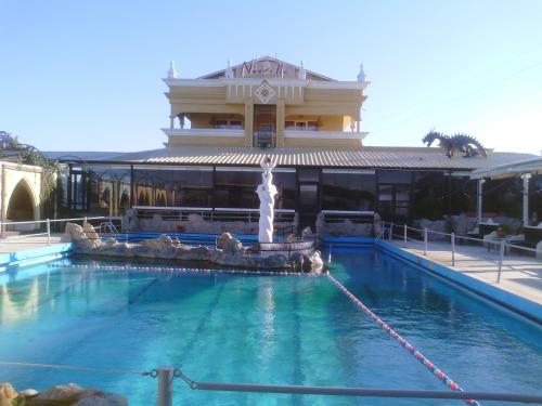 欧莱欧卡斯特伦诺威尔酒店的一座大楼前的游泳池,带喷泉