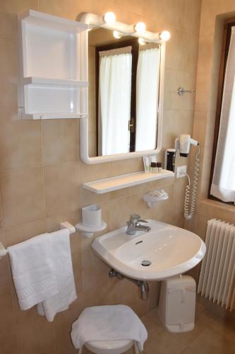 平佐洛Hotel Ferrari的一间带水槽、镜子和卫生间的浴室