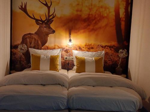 HooghalenBed en Breakfast Het Oelenest的卧室配有两张床,墙上挂着鹿头