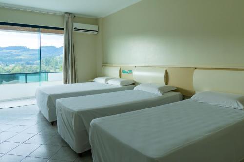圣卡洛斯Pratas Thermas Resort的带大窗户的客房内的三张床