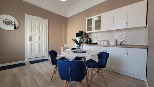 久洛Glamour Apartman的厨房配有白色的桌子和蓝色的椅子