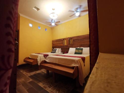 EkpedzHotel Tihosuco Colonial的黄色墙壁客房的两张床