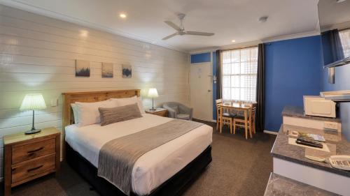 扬Colonial Motel & Apartments的一间卧室配有一张床和一张书桌,配有一张四柱床
