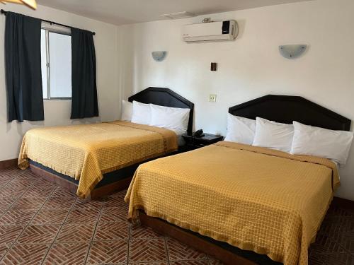 恩塞纳达港Hotel La Quinta Bonita的酒店客房设有两张床和窗户。