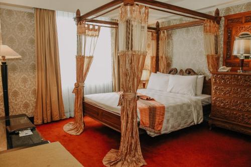 哥伦打洛省哥伦打洛酒店的一间卧室配有一张带窗帘的四柱床