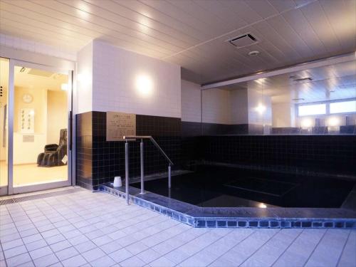 池田Green Rich Hotel Osaka Airport的带浴缸和黑色瓷砖的浴室