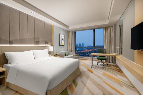 无锡无锡太湖新泽假日酒店的配有一张床、一张书桌和一扇窗户的酒店客房