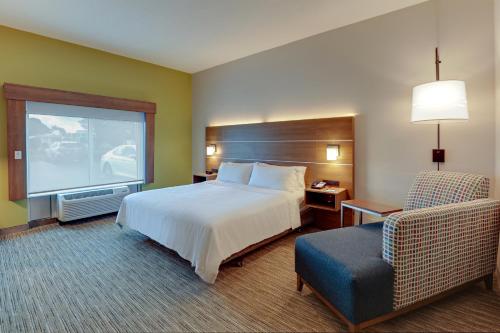 Campbellsville坎贝尔斯维尔智选假日酒店的配有一张床和一把椅子的酒店客房