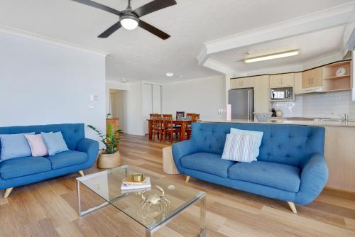 黄金海岸棕榈海滩假日公寓酒店的客厅配有2张蓝色的沙发和1张桌子