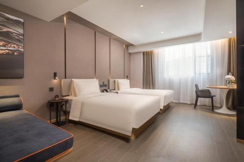 南通南通金沙亚朵酒店的酒店客房设有两张床和一张桌子。
