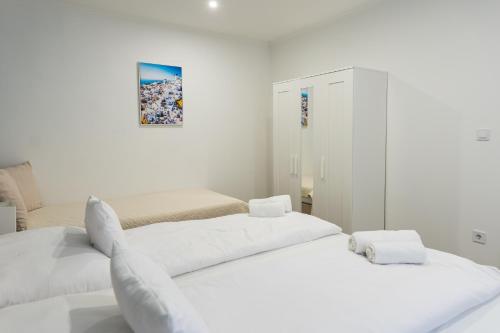 毛科MYKONOS APARTMAN的白色的客房设有两张床和橱柜。