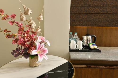 加尔各答Brio Hotel的花瓶,花朵粉红色,坐在桌子上