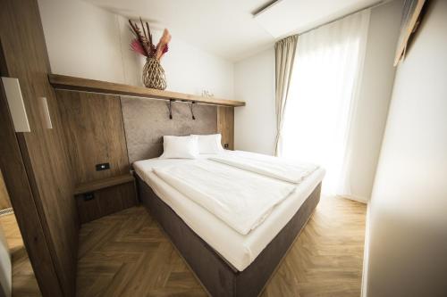 路茨曼贝格Sonnenthermen Chalets & Therme included - auch am An- & Abreisetag!的一间卧室配有一张带白色床单的床和一扇窗户。
