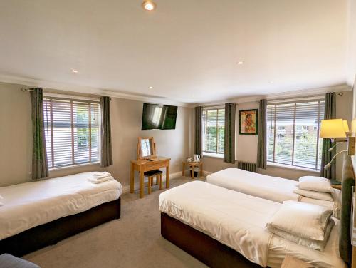 伯恩茅斯名流酒店（原品质伯恩茅斯酒店）的一间卧室设有两张床、一张桌子和窗户。
