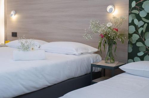 古比奥Hub Hotel的两张带白色枕头的床和一张桌子上的花瓶