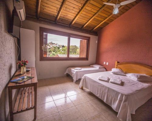 普腊亚罗萨Pousada do Mica的一间卧室设有两张床和窗户。