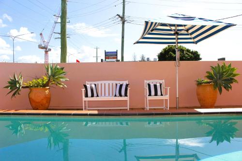 黄金海岸卡姆登汽车旅馆的游泳池旁的两把椅子和一把遮阳伞