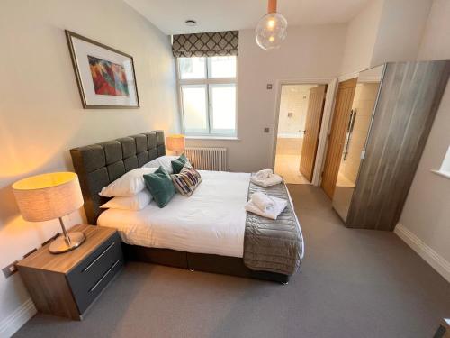 温莎Urban Living's - Windsor Castle Luxury Apartments的一间卧室配有一张床和一张桌子上的台灯