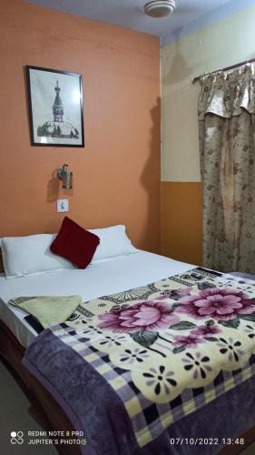 拉明德The Lumbini Village Lodge的一间卧室配有一张带花卉图案的毯子的床