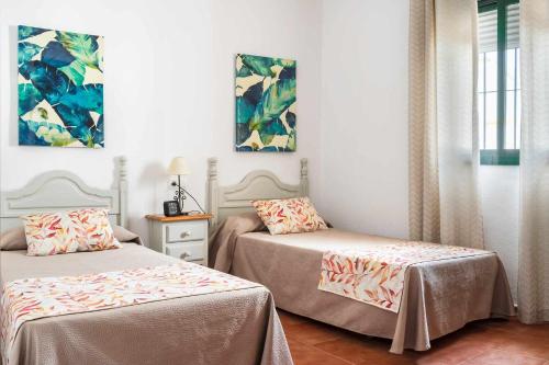 加的斯Chalet Chaparrillo Conil Alquileres Atardecer的一间卧室设有两张床和窗户。