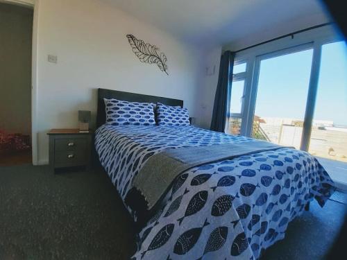 布里克瑟姆The Getaway - Modern 2 Bedroom Brixham Bungalow with sea peeps的卧室配有蓝色和白色的床,设有窗户