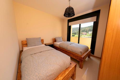 San Martín de ArribaApartamento Pinto Playa de Langosteira en Finisterre con vistas al mar的一间卧室设有两张床和窗户。