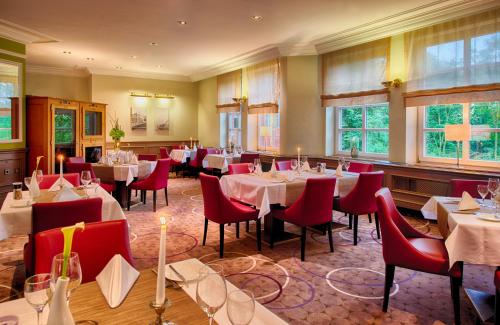 汉堡莱昂纳多汉堡斯特尔红酒店的餐厅设有桌子和红色椅子以及窗户。