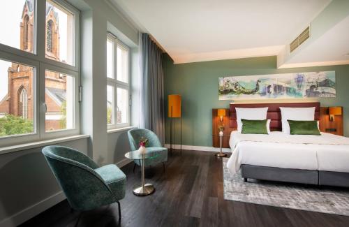 柏林柏林亚历山大广场莱昂纳多皇家酒店的一间卧室配有一张床和两把椅子